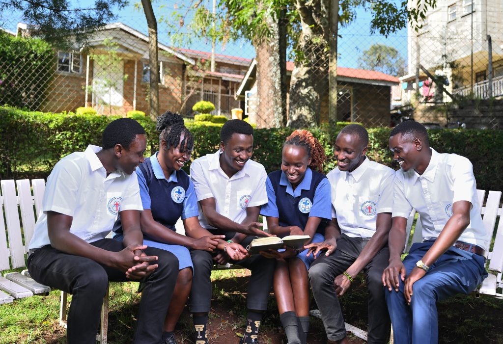 A group of students in uniform reading together on benches outdoors